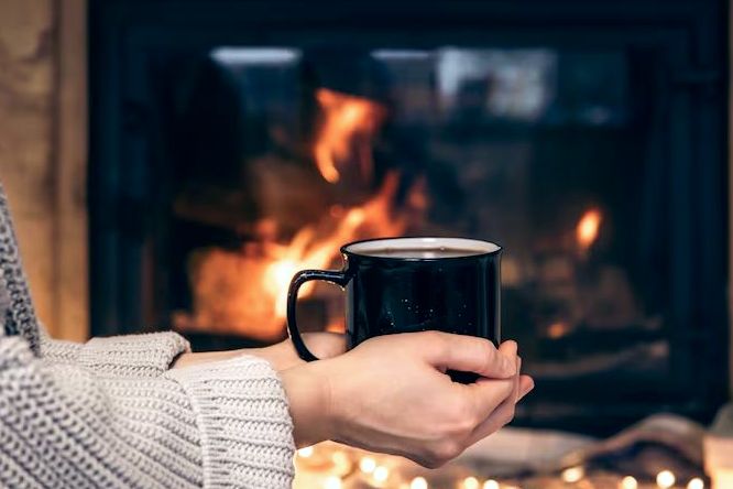 Warm mug held before a glowing, well-drafted fire